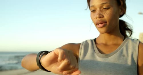Frau benutzt Smartwatch am Strand