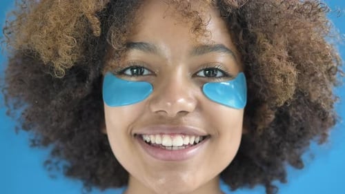 Young Woman Applies Light Blue Eye Patches