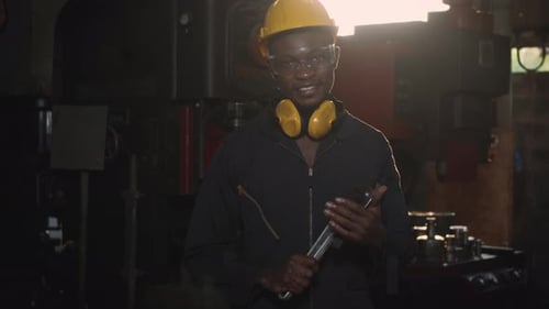 Engineer standing holding wrench on his hand at work in industry factory