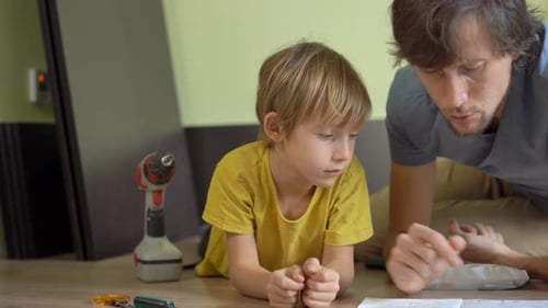 Un jeune père et son fils assemblent des meubles