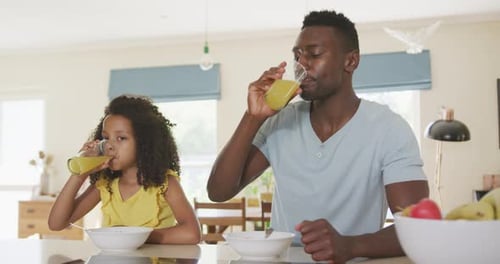 Father and Daughter Drinking Juice at Breakfast