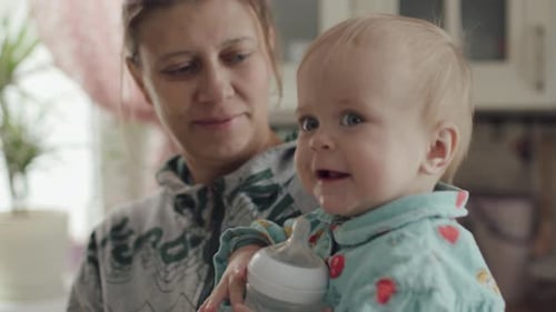 Loving Mother Feeds Baby with Bottle at Home