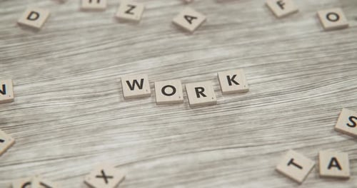 Wooden Letter Tiles Spell WORK on a Textured Wood Surface