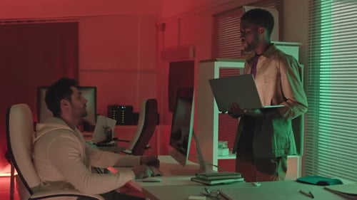 Men Working in Colorful Urban Office at Night