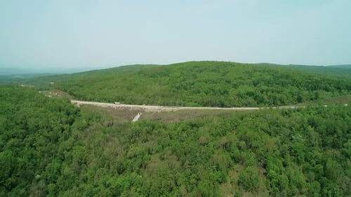 Aerial Side View of an Asphalt Intercity Country Road Between Green Forest with Vehicles Driving on