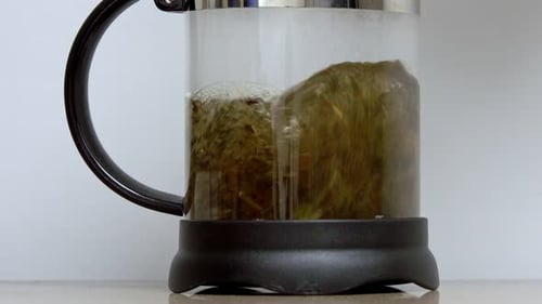 Hot Water and Tea Leaves in Glass Teapot