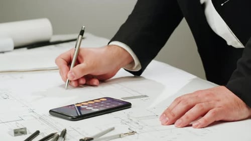 Architect Designer Counting on a Calculator Drawing Plan Blueprint Closeup
