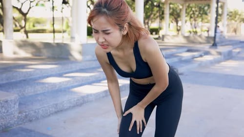 Woman Holding Knee in Pain Outdoors