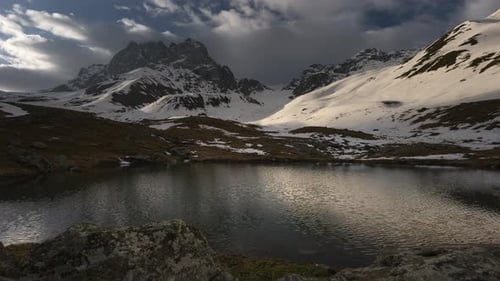 Zeitraffer aus Wolken, schneebedeckte Berge und ein See