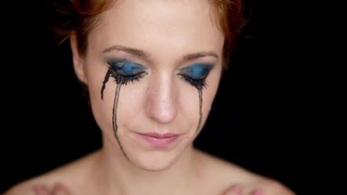 Woman's Face with Black Tears and Heavy Makeup