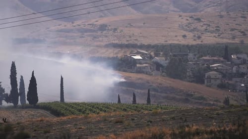 Thick smoke rising next to a village