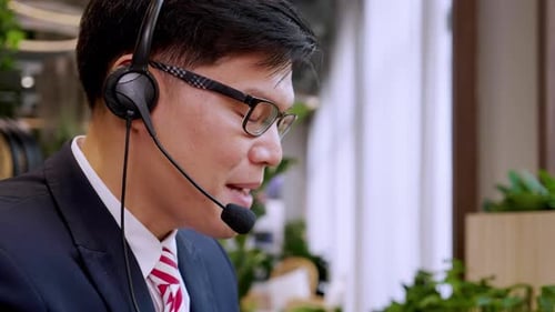 Businessman wearing telephone headset talking to caller in customer services department
