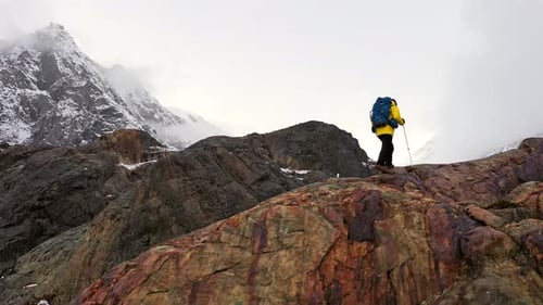 Young Man Yellow Jacket Walking Up Mountain Slope Backpacking Winter Hike Extreme Conditions Swiss