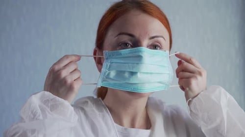 Woman Puts on a Protective Surgical Mask