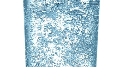 Agua con gas en vaso sobre fondo blanco, cámara lenta