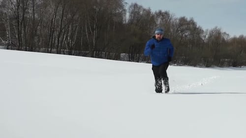 Man Running Across a Snow-Covered Field in Winter