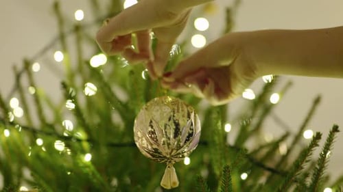 Hands decorating a Christmas tree with ornaments