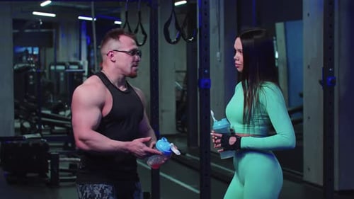 Man and Woman Talking and Drinking Water in the Gym