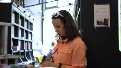 Young Woman Buying Book in a Bookstore