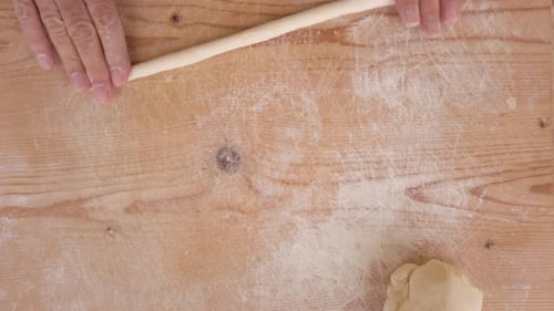 Hands Shaping Dough on Wooden Surface