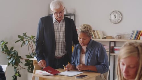 Teacher Assisting Student at Desk in Classroom