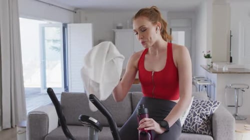 Woman Using Elliptical Machine Wipes Sweat