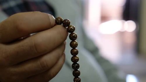 Close Up of Hand Holding Prayer Beads