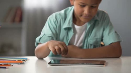 Afro-American Boy Playing on Tablet Instead of Doing His Homework Addiction