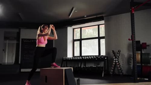 Woman athlete doing cardio exercise with lifting on pylo box in the gym.
