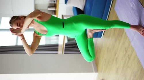 Woman Practices Yoga Balance Pose on Mat Indoors