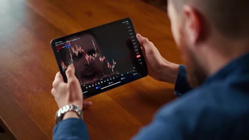 Man Analyzes Market Data on Tablet Device