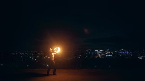 Shirtless Man Juggling Flaming Torches at Night
