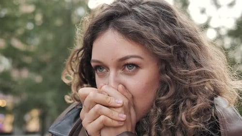 Une fille souffle de l'air chaud et se frotte les mains gelées en attendant à l'extérieur