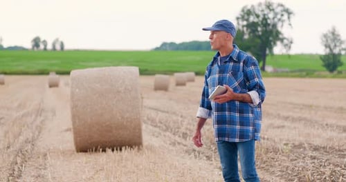 Farmer Using Digital Tablet While Examining Field