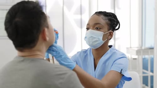 Crop View of Medical Female Nurse in Protective Mask and Gloves Taking Swab From Nose of Man in