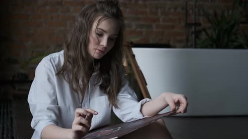 Girl Painter Paints a Picture with Brushes. Portrait of a Cute Girl in a Home Studio
