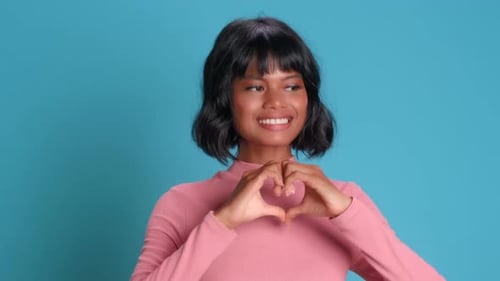 Woman Makes Heart Shape with Hands on Blue Background