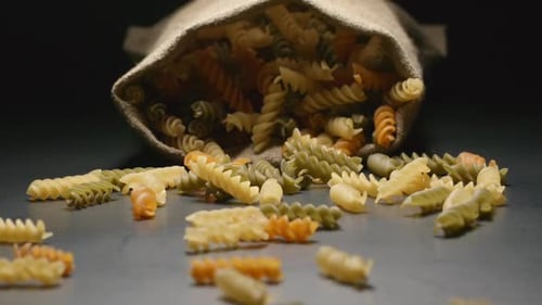 Cloth bag falls and colour pasta (fusilli) fall out of him