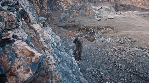 The Soldier of Special Forces Moves Along a Gorge in the Mountains with Machine Gun During Military