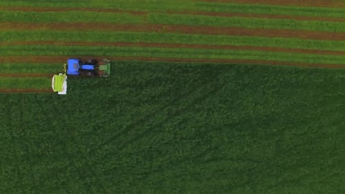 Luftaufnahme eines Traktors, der das Gras auf einer großen grünen Wiese mäht.