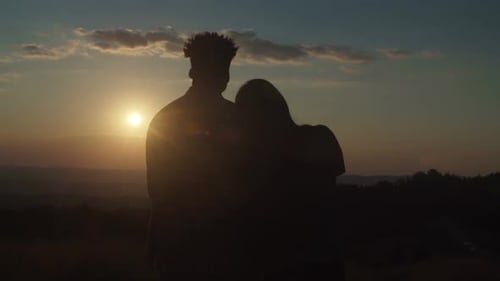 Silhouette of Couple Standing in Love Embrace Enjoying Scenic Mountain Nature at Sundown
