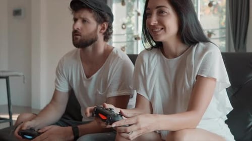 Couple Playing Video Games on Couch Together Indoors