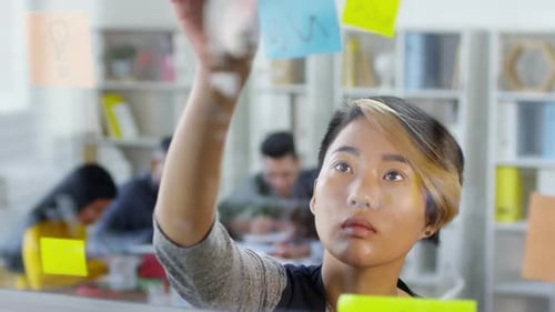 Young Asian Employee Putting Up Memos