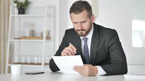Homme d'affaires pensif lisant des documents au bureau, paperasse