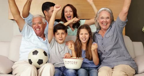 Família feliz assistindo futebol na tv