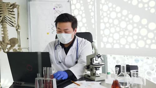 Korean Male Research Ander Microscope, then Typing Results of the Test on Computer