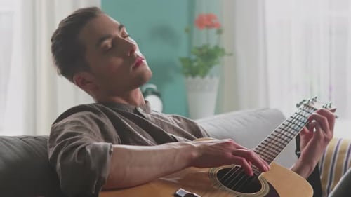 Man Playing Acoustic Guitar Relaxing on Sofa