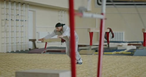 Tracking Shot of Energetic Young Male Gymnast Performing Acrobatic Trick with Triple Flip While