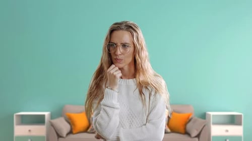 Hmm. Verdächtige nachdenkliche junge Frau schaut auf, Hand auf ihrem Gesicht halten, als ob sie sich sehr bemühen würde