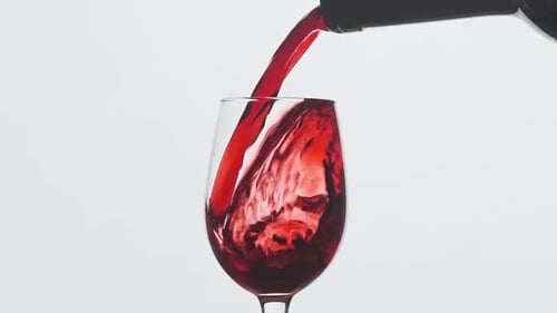 Red Wine Pouring From Bottle Into Goblet. Rose Wine Pouring in Wine Glass
